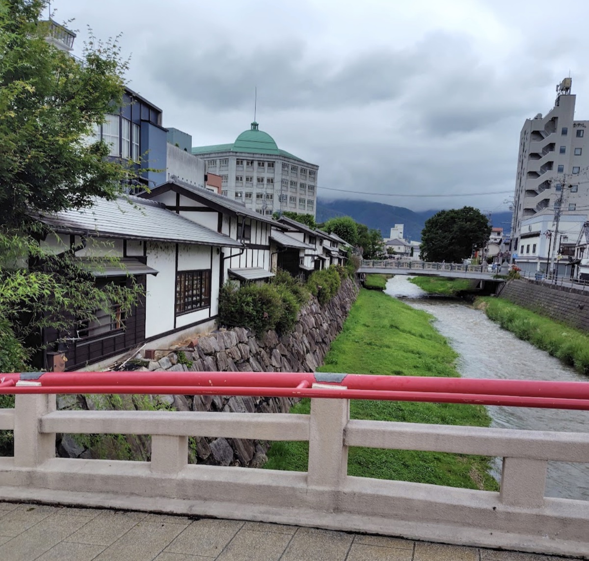 女鳥羽川の風景。赤い欄干の橋と、川沿いの古い街並み